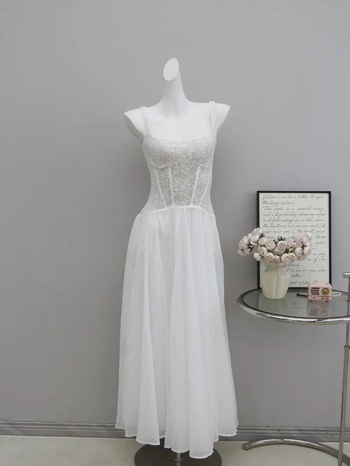 White sleeveless A-line dress with a delicate floral lace bodice and a flowing sheer mid-calf skirt, presented on a mannequin against a studio background.