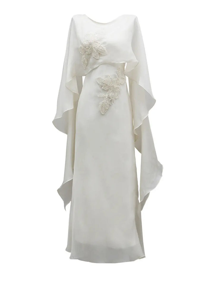 Elegant ivory satin column gown with delicate pearl and bead floral embroidery on the bodice and hip, featuring a flowing sheer chiffon cape. Floor-length, boat neckline.